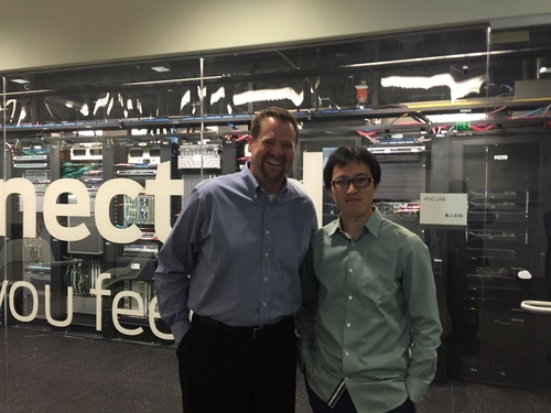 Our tour guides: Juniper Major Account Manager Jesse Burmeister (left) and Senior Systems Engineer Xiao Wang. The lab is behind the glass wall. The lettering on the glass wall says, 'Your ideas, connected (Can you feel it?).'