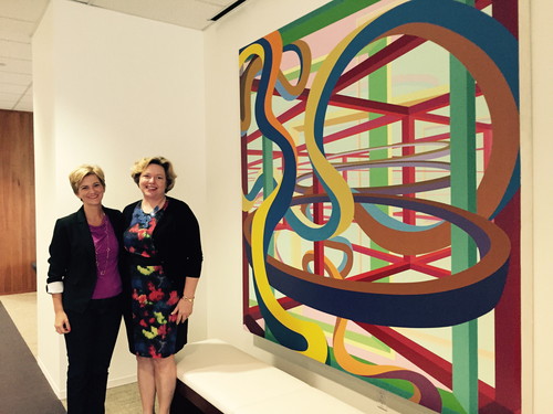 Brooks McCorcle, president (right) and Sue Galvanek, VP - Marketing, Pricing and Product Solutions, pose at the AT&T Partner Solutions office in Plano, alongside artwork McCorcle specifically brought in from AT&T's collection. The painting, Vorcex III by Al Held, had hung in the St. Louis office of the former Southwestern Bell, where McCorcle began her career. Throughout the AT&T Partner Solutions space, artwork is used for inspiration and diversion.
