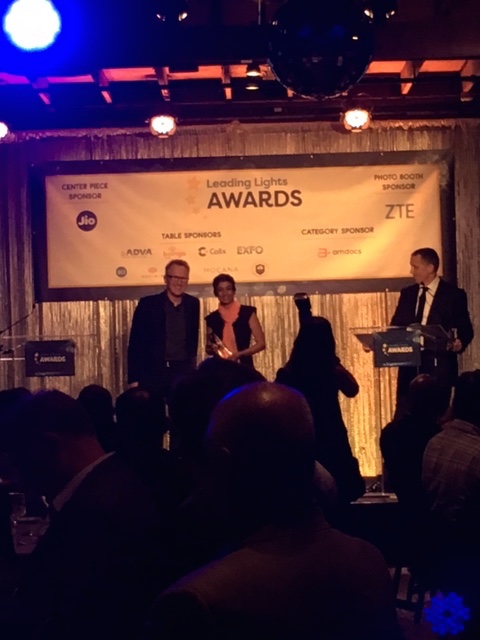 Nextleaf's Nithya Ramanathan accepts her award from Light Reading's Ray Le Maistre as the paparazzi and audience looks on.