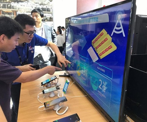 China Mobile booth visitor observing the Gigabit LTE demo with the Samsung Galaxy S8, and getting an explanation of the three technologies underlying Gigabit LTE: carrier aggregation, 4x4 MIMO and 256-QAM.
