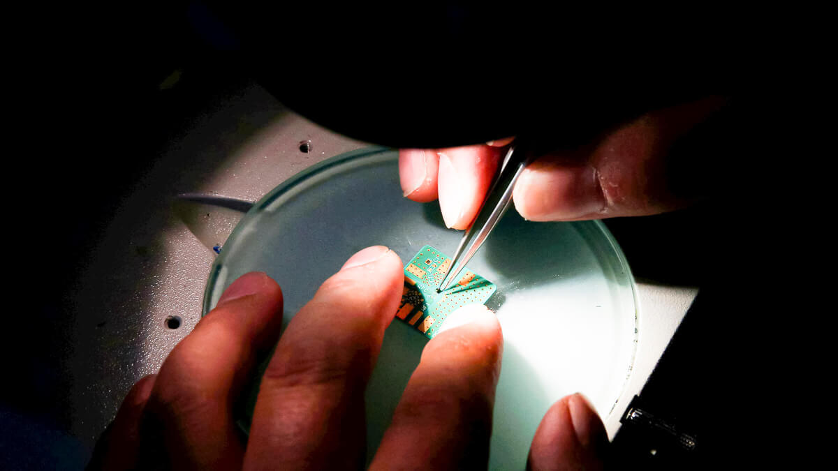 A researcher plants a semiconductor on an interface board at Tsinghua Unigroup research centre in Beijing. (Source: REUTERS / Alamy Stock Photo)