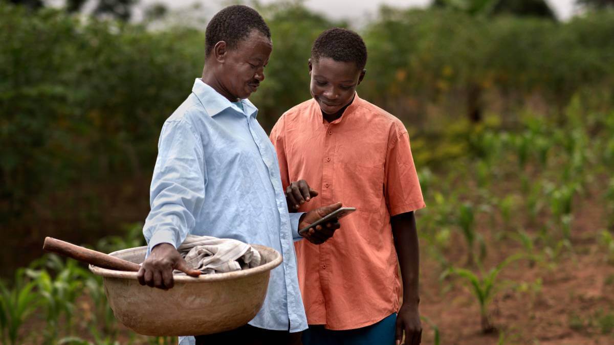 An African farmer and his son using a mobile app on a smartphone.  (Source: African farmer photo created by freepik - www.freepik.com) 